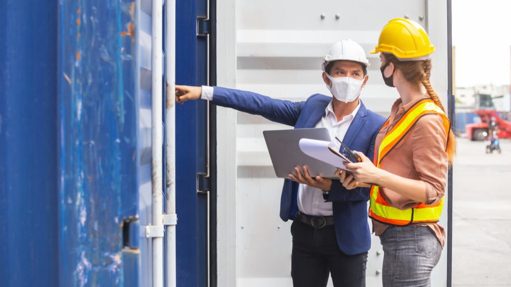 Teamwork foreman man and woman wearing protection face mask and safety helmet using laptop and holding clipboard checking containers in cargo ship for import export, Industrial container cargo concept.
 (Teamwork foreman man and woman wearing protecti